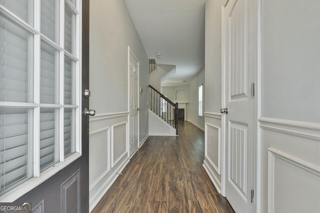 interior space featuring wainscoting, stairway, dark wood finished floors, and a decorative wall