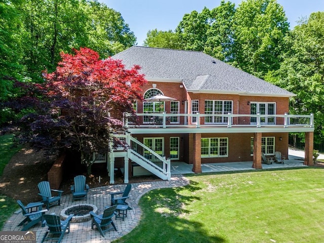 rear view of property featuring a wooden deck, a patio area, a fire pit, and a lawn