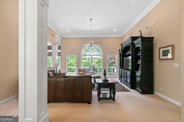 carpeted living room with decorative columns, ornamental molding, and ceiling fan