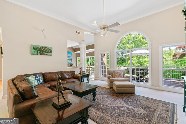 carpeted living room featuring ornate columns, crown molding, ceiling fan, and high vaulted ceiling