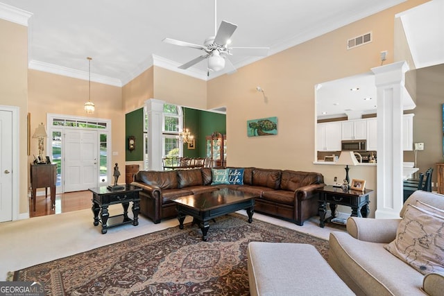 living room featuring ornate columns, ornamental molding, a towering ceiling, and ceiling fan