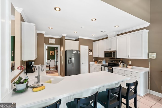 kitchen featuring sink, a breakfast bar area, stainless steel appliances, white cabinets, and kitchen peninsula