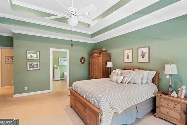 bedroom with a raised ceiling, crown molding, light carpet, and ensuite bathroom