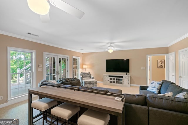 carpeted living room featuring ornamental molding, french doors, and ceiling fan