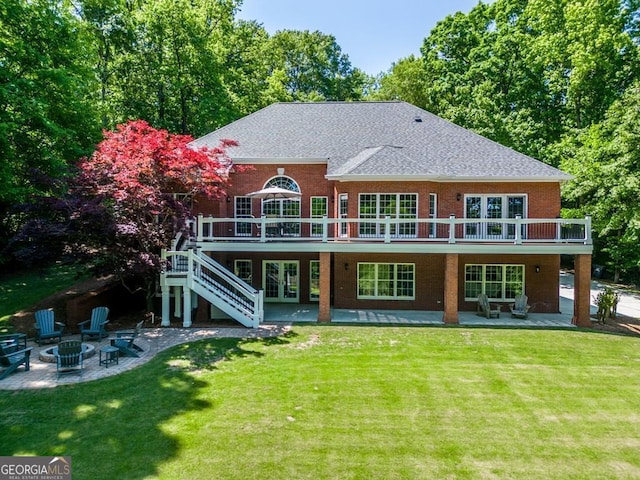 rear view of house with a patio, a lawn, a deck, and a fire pit