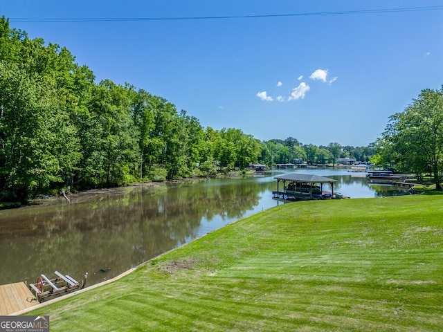 view of dock with a yard and a water view