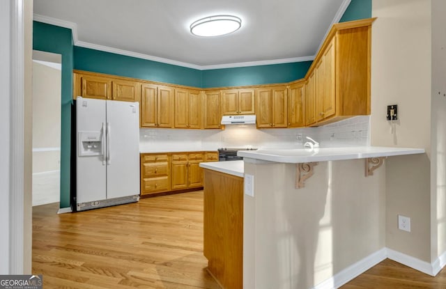 kitchen with a breakfast bar, tasteful backsplash, white refrigerator with ice dispenser, kitchen peninsula, and light wood-type flooring