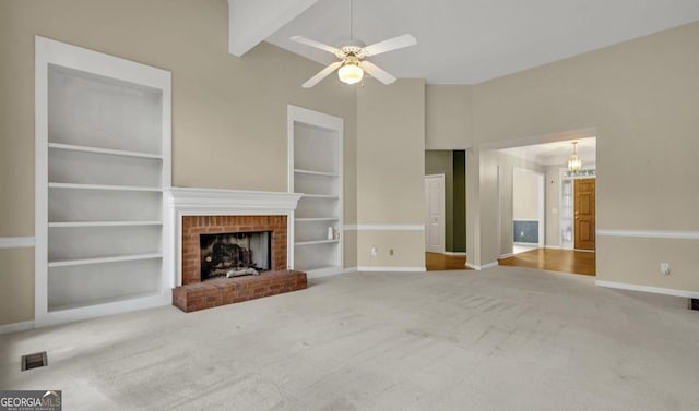 unfurnished living room with a brick fireplace, built in shelves, vaulted ceiling with beams, and carpet flooring