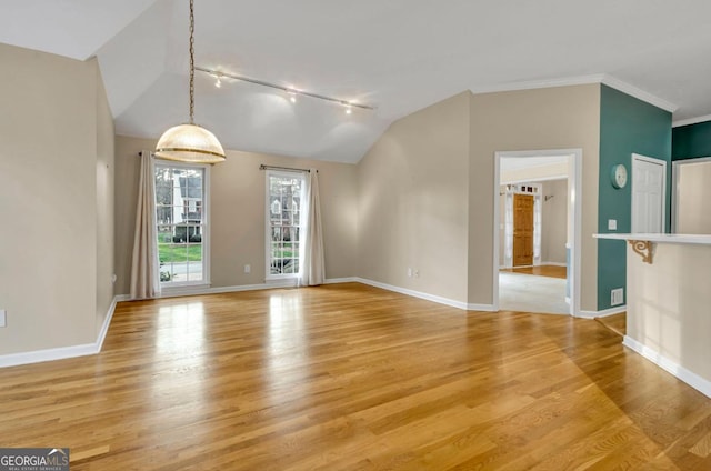 unfurnished living room featuring crown molding, track lighting, lofted ceiling, and light hardwood / wood-style floors