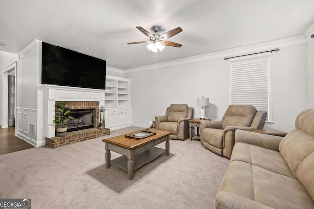 living area featuring ceiling fan, a fireplace, carpet flooring, and crown molding