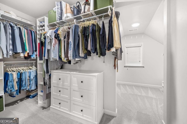 spacious closet featuring light carpet, visible vents, and vaulted ceiling