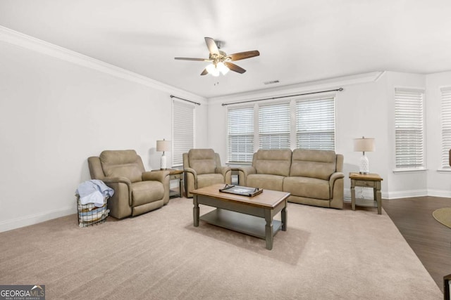 living room with baseboards, ceiling fan, visible vents, and crown molding