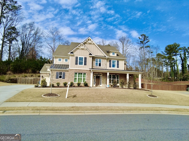 craftsman-style home with brick siding, board and batten siding, fence, concrete driveway, and covered porch