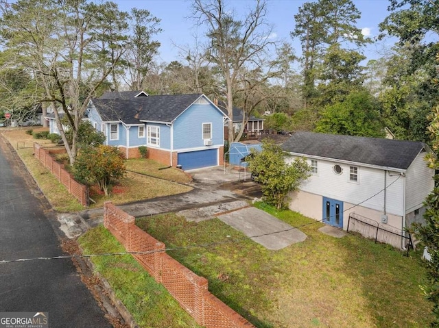 view of front of house with an attached garage, concrete driveway, a front yard, and fence