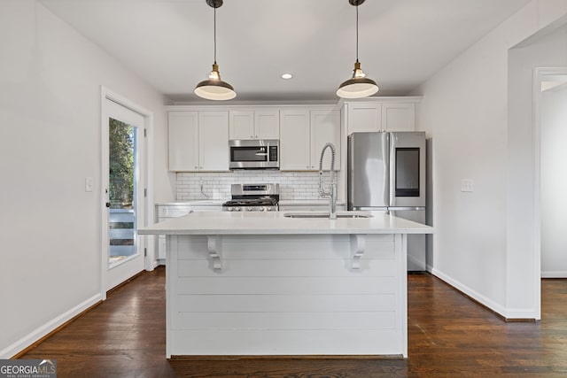 kitchen with stainless steel appliances, hanging light fixtures, a center island with sink, and white cabinets