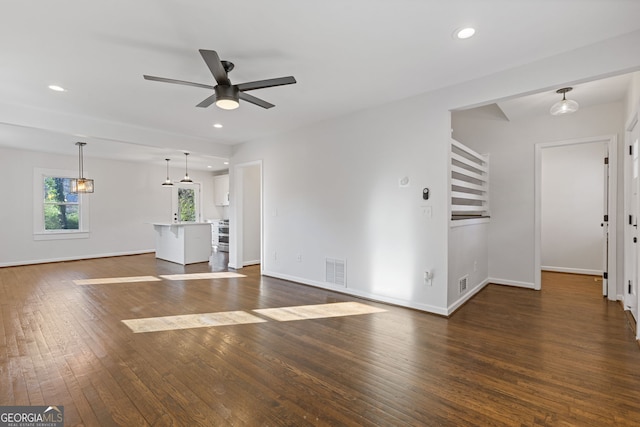 unfurnished living room featuring ceiling fan and dark hardwood / wood-style flooring