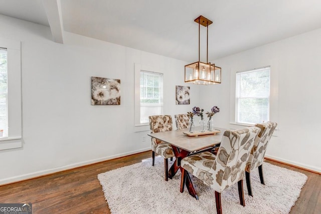 dining room with beamed ceiling, dark wood-type flooring, and a wealth of natural light