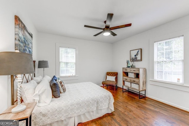 bedroom with multiple windows, wood-type flooring, and ceiling fan