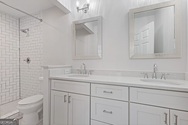 bathroom with a tile shower, vanity, and toilet