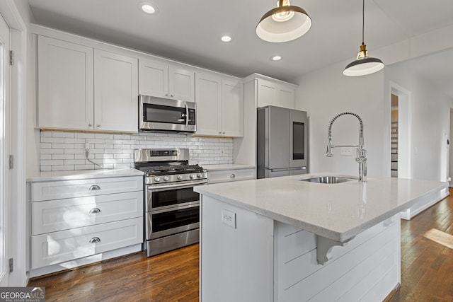 kitchen featuring sink, stainless steel appliances, white cabinets, and a center island with sink