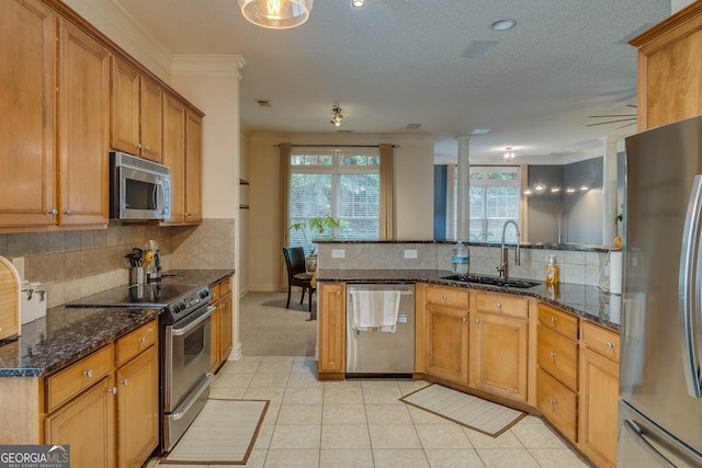 kitchen featuring appliances with stainless steel finishes, sink, light tile patterned floors, and dark stone counters