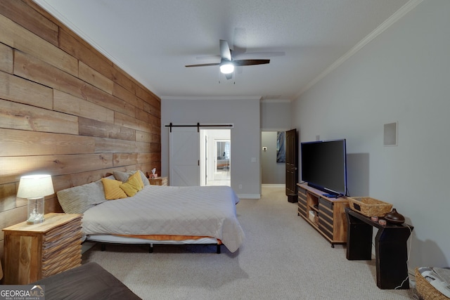 bedroom with wood walls, ceiling fan, crown molding, a barn door, and light carpet