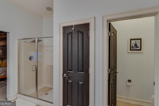 bathroom with a shower with door, crown molding, and toilet