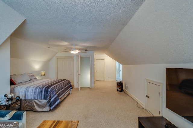 carpeted bedroom featuring ceiling fan, a closet, vaulted ceiling, and a textured ceiling