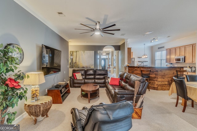 carpeted living room with ornamental molding and ceiling fan