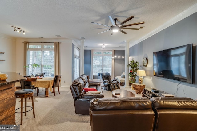 carpeted living room featuring ceiling fan, ornamental molding, a textured ceiling, and ornate columns