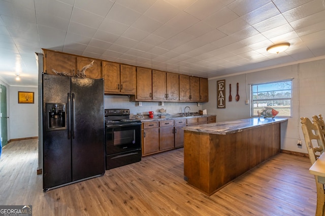 kitchen with ornamental molding, black appliances, and light wood-type flooring