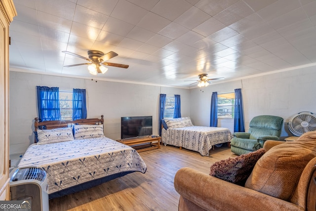 bedroom featuring multiple windows, ornamental molding, and light wood-type flooring