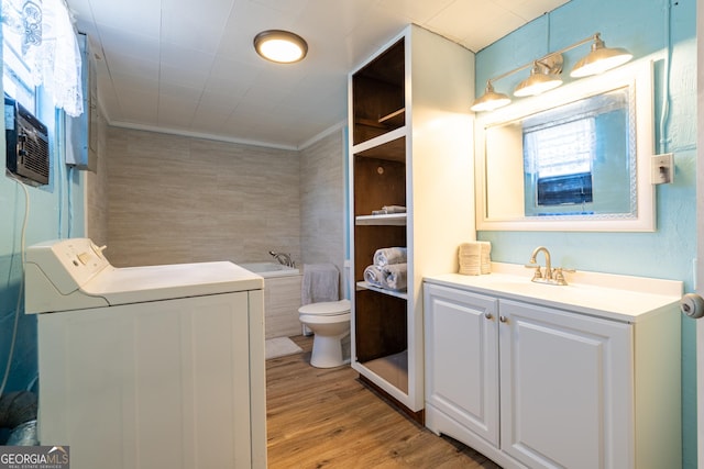 bathroom featuring wood-type flooring, washer / dryer, vanity, toilet, and crown molding