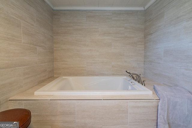 bathroom featuring tiled tub, ornamental molding, and tile walls