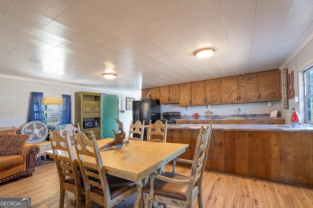 dining area with crown molding, sink, and light wood-type flooring