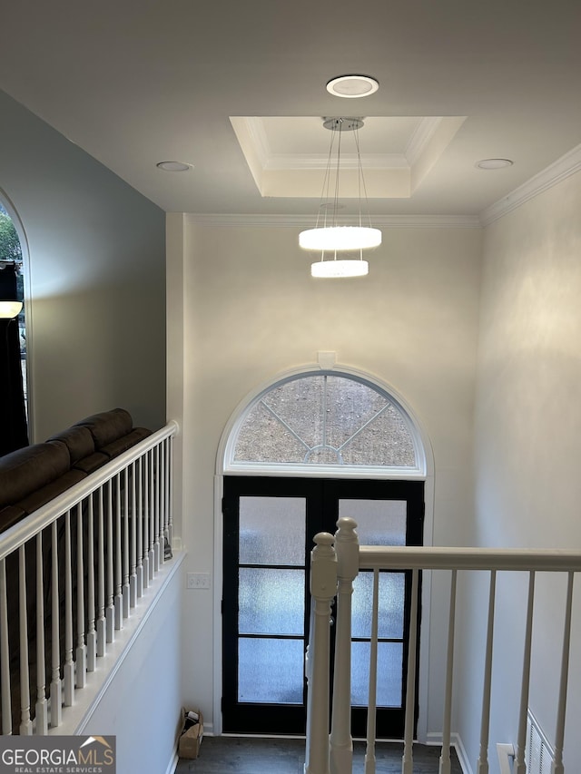 foyer entrance featuring a raised ceiling, crown molding, and a towering ceiling