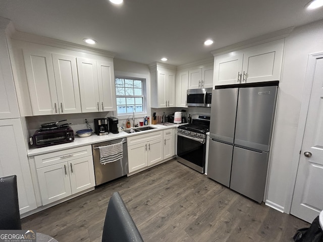 kitchen with dark hardwood / wood-style flooring, sink, stainless steel appliances, and white cabinets