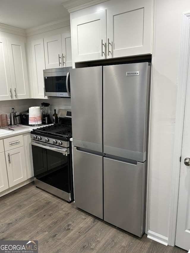 kitchen with white cabinetry, appliances with stainless steel finishes, and hardwood / wood-style floors