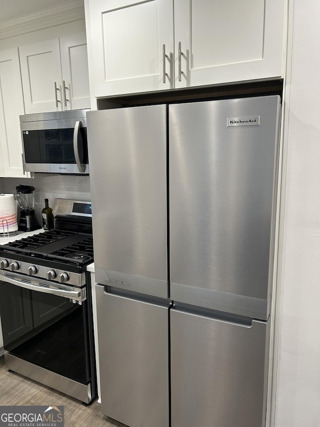 kitchen with white cabinetry, appliances with stainless steel finishes, light wood-type flooring, and decorative backsplash