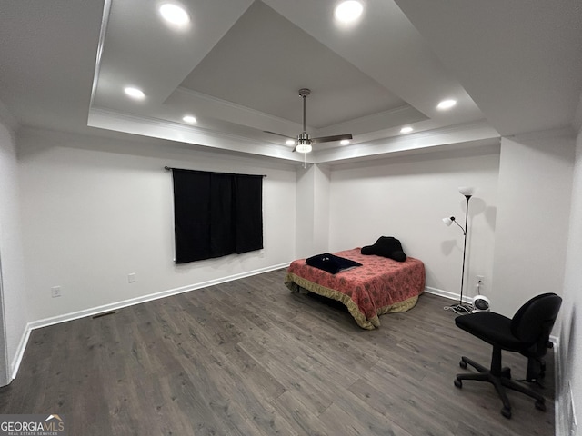 bedroom with a raised ceiling, ornamental molding, and dark wood-type flooring