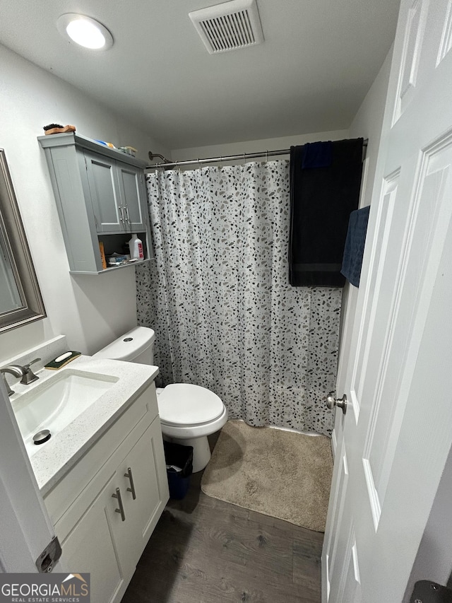 bathroom with hardwood / wood-style flooring, vanity, walk in shower, and toilet