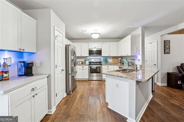 kitchen with sink, appliances with stainless steel finishes, white cabinetry, light stone countertops, and dark hardwood / wood-style flooring