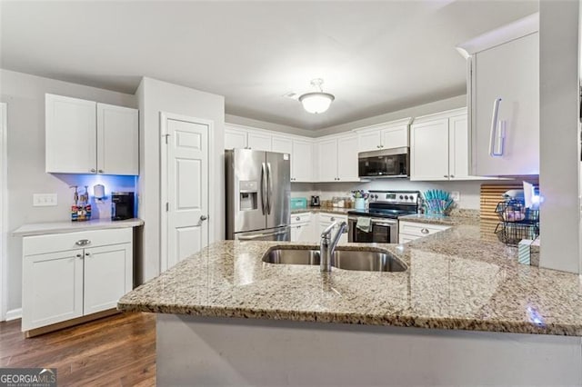 kitchen with white cabinetry, appliances with stainless steel finishes, light stone counters, and kitchen peninsula