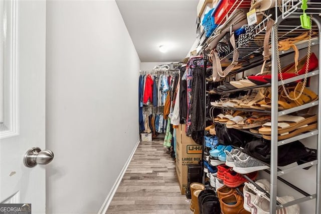 walk in closet with light hardwood / wood-style flooring