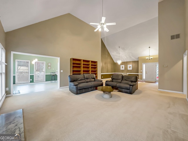 carpeted living room featuring ceiling fan with notable chandelier and high vaulted ceiling