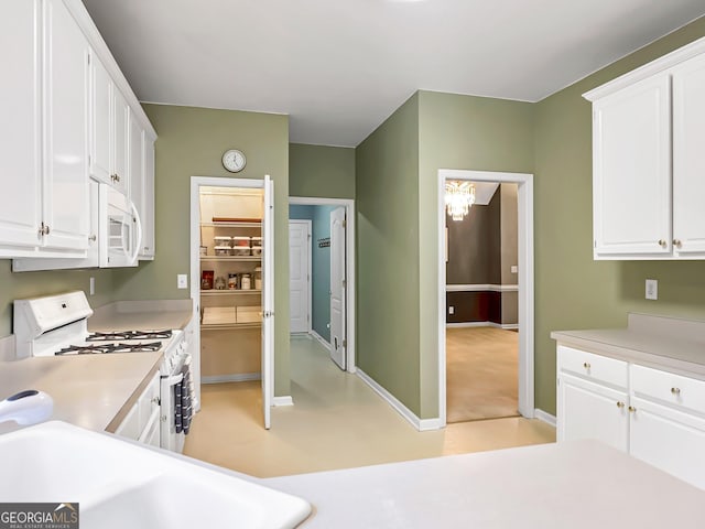 kitchen with sink, white cabinets, and white appliances