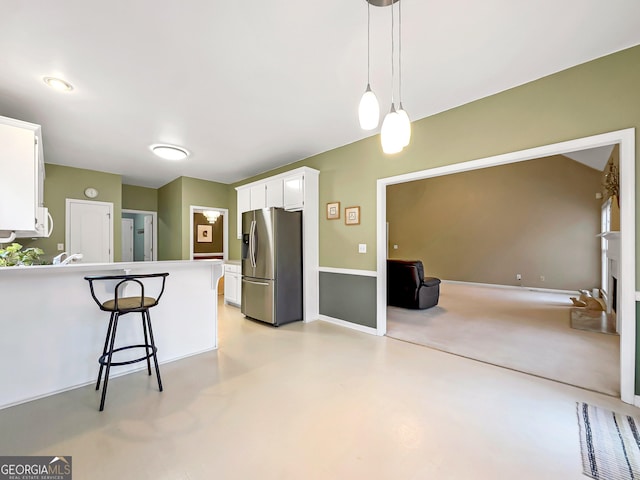 kitchen with a breakfast bar, white cabinetry, hanging light fixtures, stainless steel fridge with ice dispenser, and kitchen peninsula