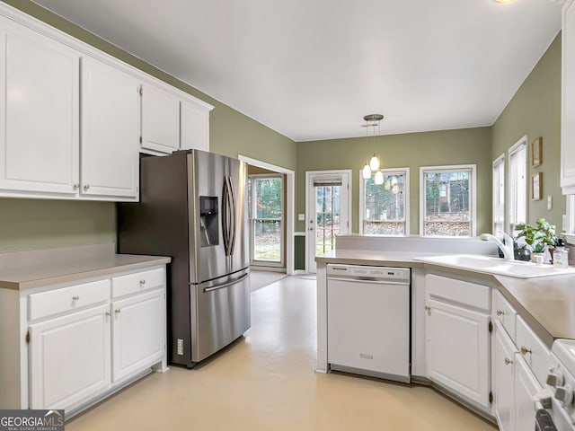 kitchen with white appliances, sink, hanging light fixtures, and white cabinets