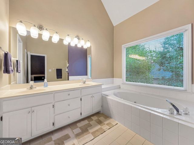 bathroom with tiled tub, vanity, lofted ceiling, and tile patterned floors