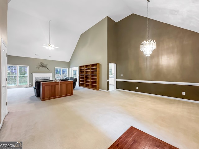 kitchen with ceiling fan with notable chandelier, high vaulted ceiling, a high end fireplace, light carpet, and decorative light fixtures